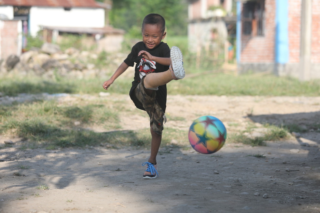 Un petit garçon avec une prothèse de jambe joue au football Népal - Projets de HI